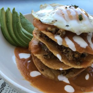 Duck Chorizo Chilaquiles: Fried tortillas in a red sauce with house made duck chorizo. Topped with jack cheese, avocado and fried egg.