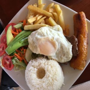 Traditional meal of steak, egg, french fries, salad and rice